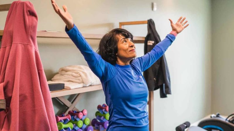 Female yoga instructor looking up with arms raised
